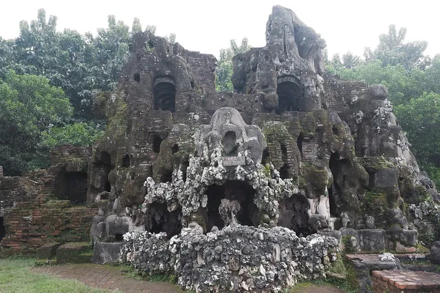 ID: Fasad bangunan berbentuk gua dengan pintu melengkung dan tekstur batu di Sunyaragi. EN: A grotto-like facade with arched openings and textured stone at Sunyaragi.