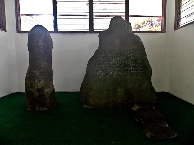 Prasasti dan batu-batu pendamping di dalam cungkup pada Maret 2024. / The inscription and accompanying stones inside the shelter in March 2024.