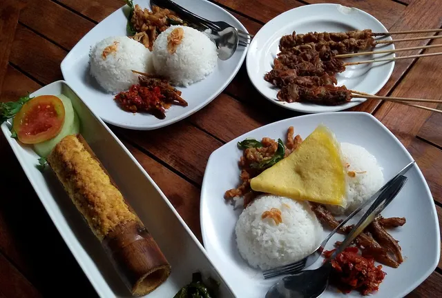 Hidangan nasi dan sate pada meja kayu di The House of Raminten, foto arsip 2014 / Rice dishes and satay on a wooden table at The House of Raminten, archive photograph from 2014