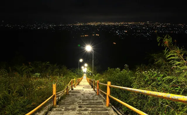 Jalur tangga di lereng Gunung Galunggung dengan lampu dan cahaya kota pada malam hari, Mei 2017. / Stairway on Mount Galunggung with lights and the town at night, May 2017.