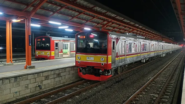 Dua rangkaian KRL berhenti di peron Stasiun Bekasi pada malam hari, Juni 2022. / Two commuter trains at Bekasi Station platforms at night, June 2022.