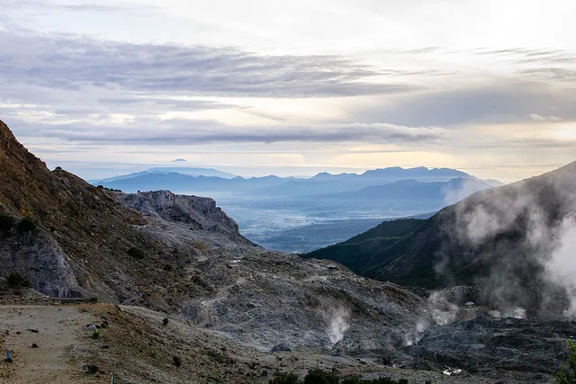 Tanah berbatu Papandayan dengan kepulan uap dan pegunungan di kejauhan, Januari 2025. / Rocky Papandayan ground with vapour and distant mountain ranges, January 2025.