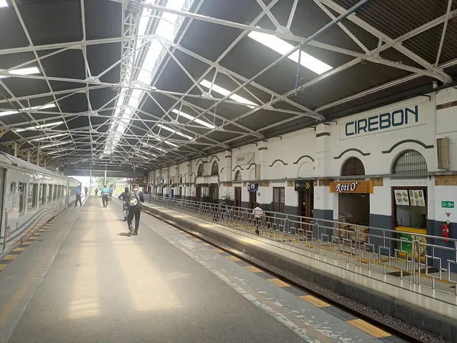 Sisi peron Stasiun Cirebon dengan rangka atap baja, bangunan lama, dan kereta, Januari 2024. / Platform side of Cirebon Station with a steel roof frame, older building and train, January 2024.