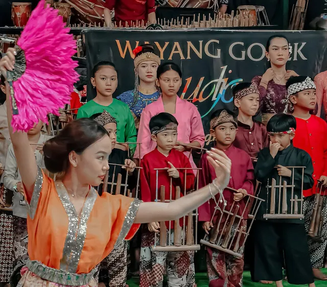 ID: Penari dan pemain angklung tampil bersama di Saung Angklung Udjo. EN: Dancers and angklung players performing together at Saung Angklung Udjo.