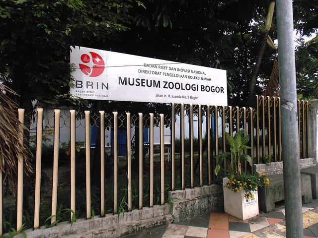 Plang BRIN bertuliskan Museum Zoologi Bogor di balik pagar kawasan museum.