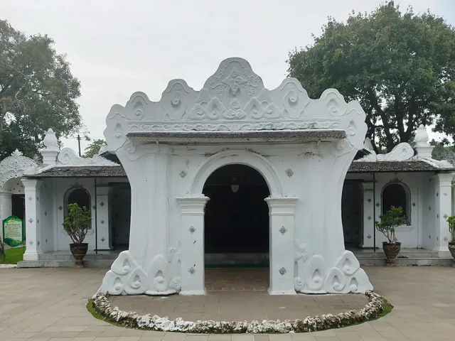 ID: Gerbang Kutagara Wadasan dengan lengkung putih dan hiasan di Keraton Kasepuhan. EN: Kutagara Wadasan gateway with a white arch and decorative details at Keraton Kasepuhan.