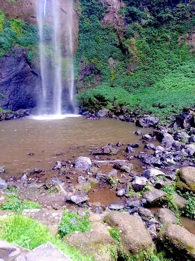 Aliran Curug Cimahi jatuh ke kolam berbatu di bawahnya. / Curug Cimahi falls into a rocky pool below.