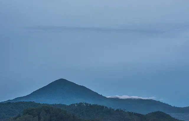 Siluet bukit Gunung Putri di kawasan Lembang di bawah langit biru.