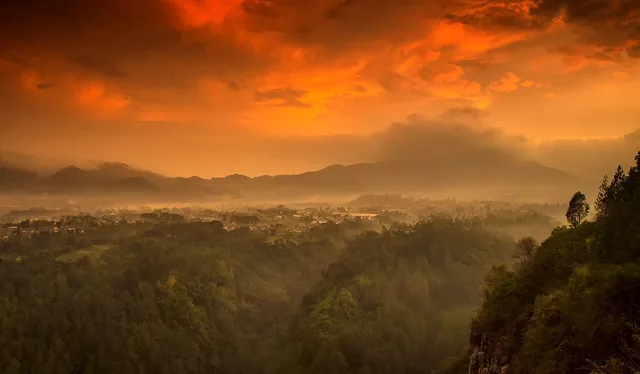 Perbukitan dan hutan dari Tebing Keraton dengan langit berwarna hangat. / Forest and hills from Tebing Keraton under a warm-coloured sky.