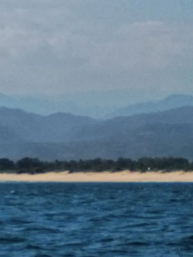 Laut di Pantai Santolo dengan garis pasir dan perbukitan di kejauhan.