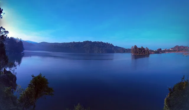 Panorama Situ Patenggang dengan pulau kecil dan perbukitan. / Situ Patenggang panorama with a small island and hills.