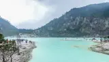 Panorama danau dan dinding Kawah Putih di Kabupaten Bandung; pengunjung tampak kecil di tepi danau.