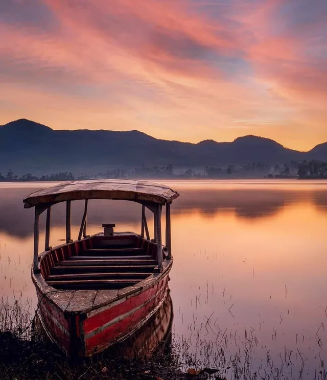 Perahu kayu di tepian Situ Cileunca dengan warna senja, tanggal sumber Mei 2022. / Wooden boat at the Situ Cileunca shore with sunset colours, source date May 2022.