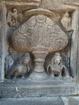 Relief batu di Prambanan dengan hiasan pohon dan sosok ukiran / Stone relief at Prambanan with a tree motif and carved figures
