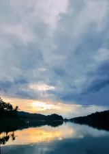 Langit senja dan pepohonan terpantul di air Waduk Sermo / Sunset sky and trees reflected in the waters of Sermo Reservoir