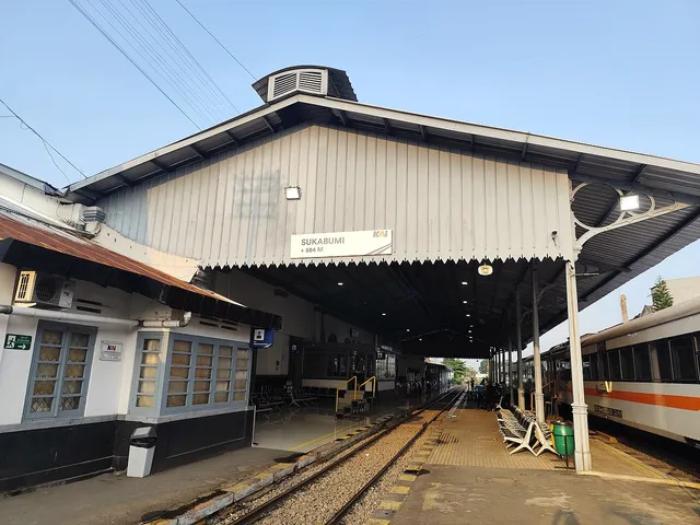 Kanopi peron Stasiun Sukabumi dengan papan nama dan kereta di sisi kanan, Juli 2024. / Sukabumi Station platform canopy with its name sign and a train to the right, July 2024.